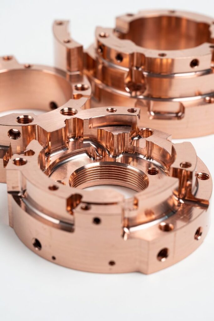 Rose-gold copper CNC precision machined ring components with internal threads and intricate stepped geometry, showcasing a warm metallic luster.
