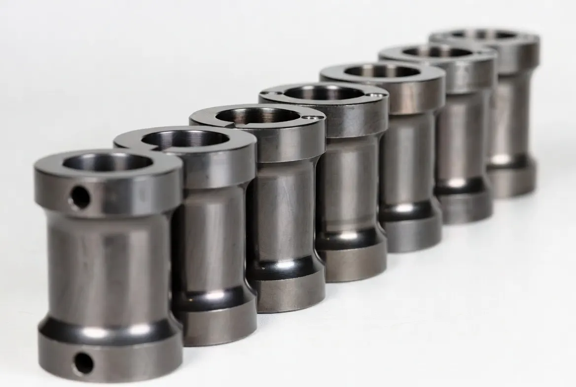 Multiple identical DLC coated CNC steel industrial shafts and connecting components arranged neatly in a row on a white background.