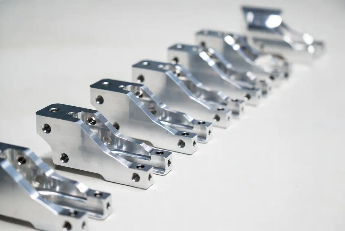 Multiple identical aluminum CNC precision brackets and connecting parts arranged neatly in a row on a white background.