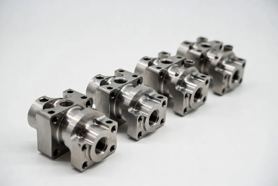 Multiple identical stainless steel CNC industrial connectors and fittings arranged neatly in a row on a white background.